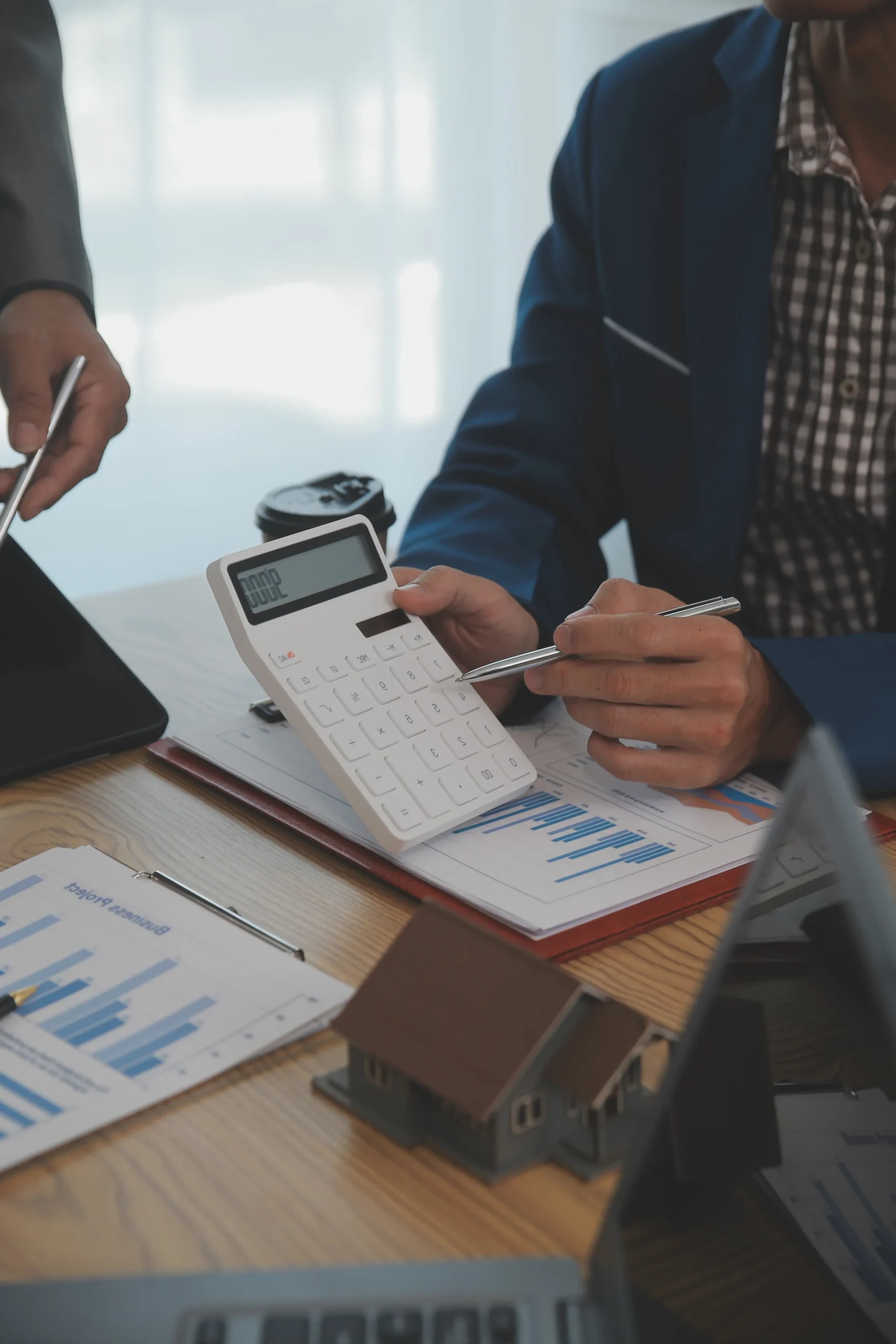 Financial professional reviewing charts and calculations with calculator and pen at a desk, discussing property finances and tax planning details