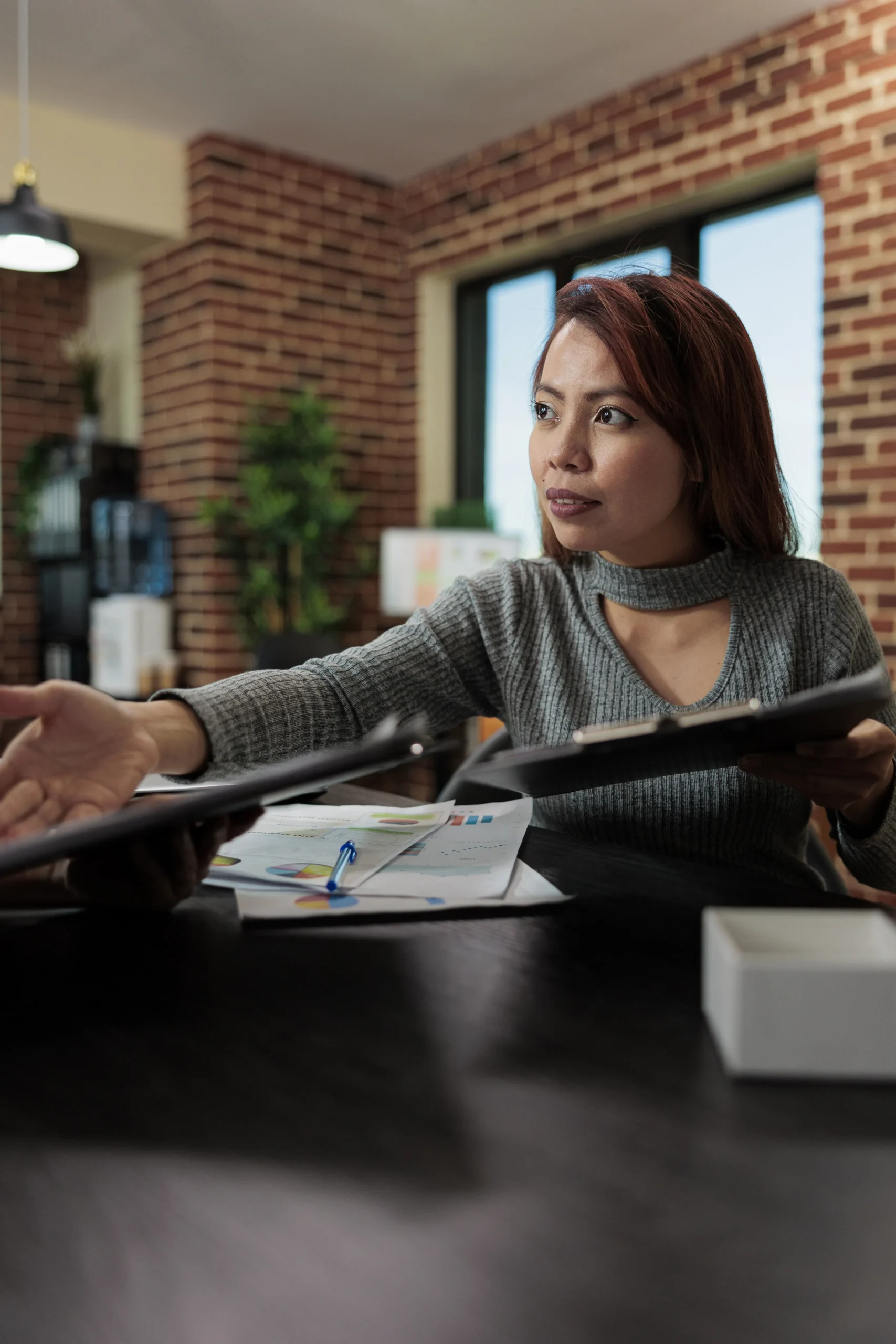 Businesswoman reviewing documents and explaining strategy during a team meeting in a modern office with charts and tablet IT